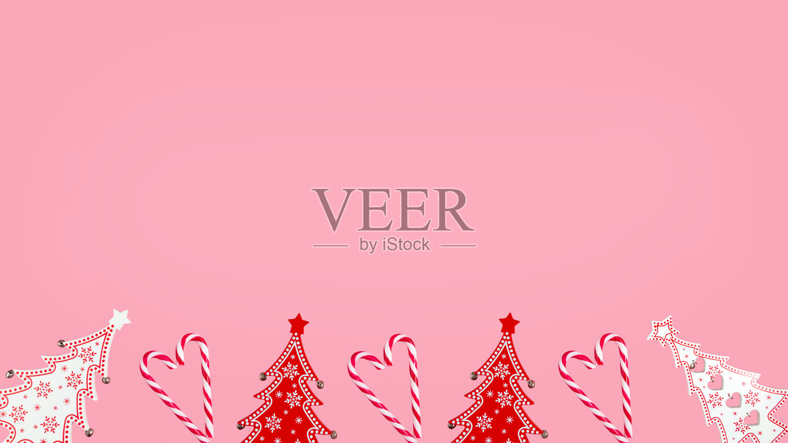 圣诞节的粉红色背景与冷杉树和条纹糖果手杖。孤立的照片摄影图片