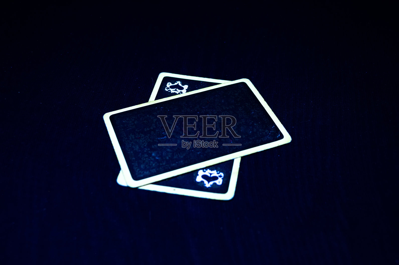 两张卡片，一张在另一张上面，晚上放在一块黑色的桌布上。照片摄影图片