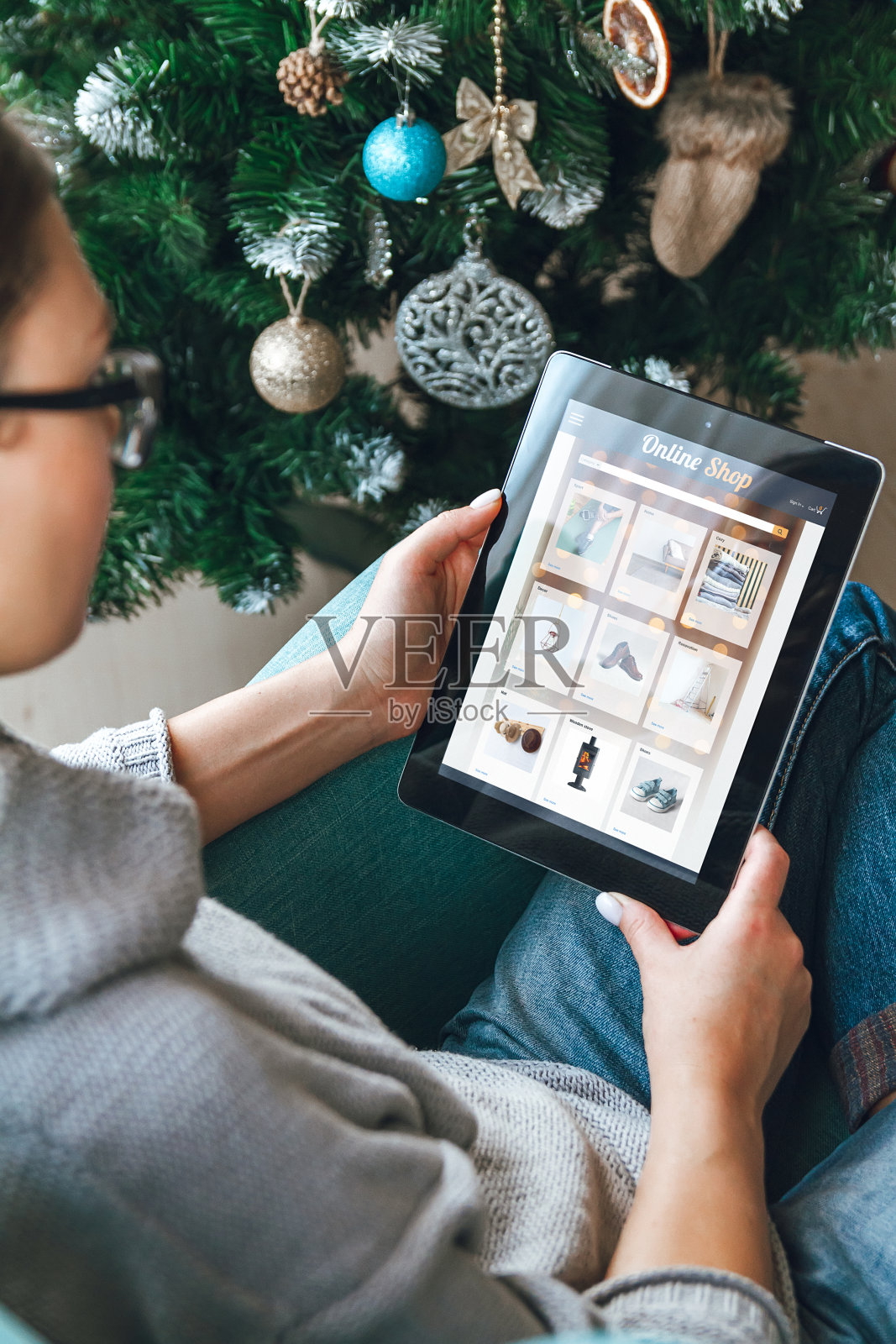 圣诞树的背景上放着一个平板电脑的年轻女子照片摄影图片