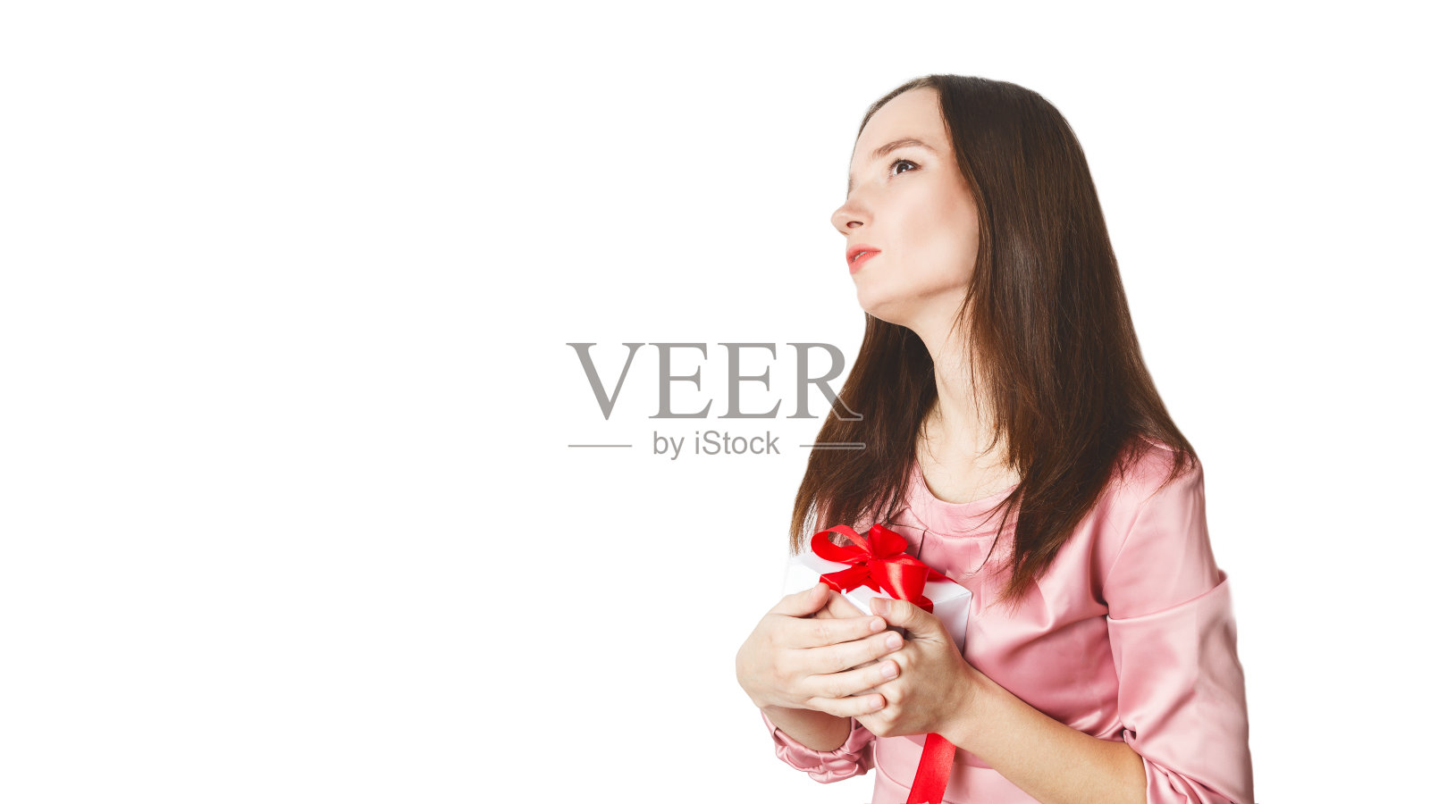 一个快乐的梦幻女孩的肖像穿着衣服拿着礼物盒。深色头发的年轻女性在节日生日时收到礼物。白色背景。情人节。一个圣诞礼物照片摄影图片