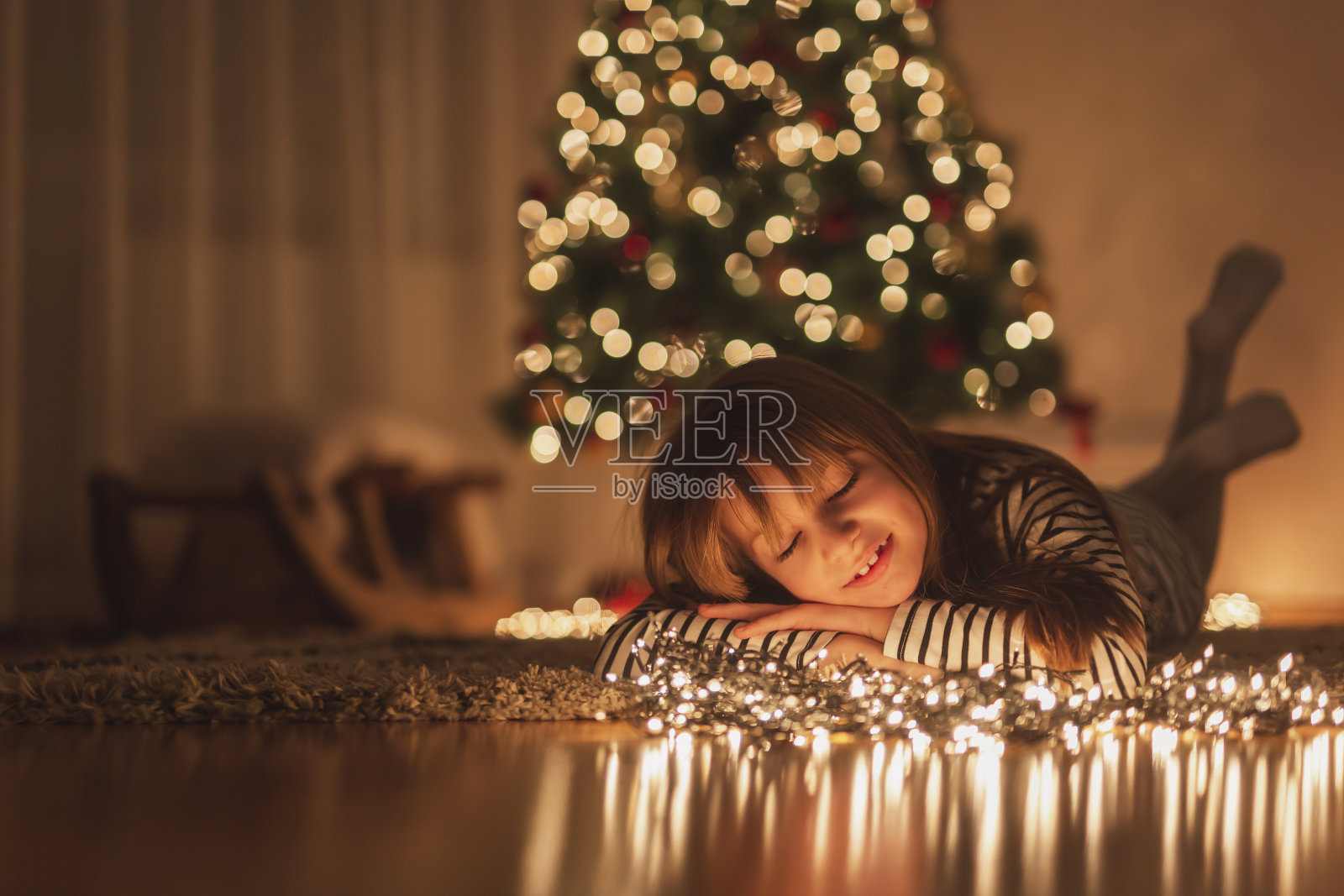 小女孩躺在地板上，周围都是圣诞彩灯照片摄影图片