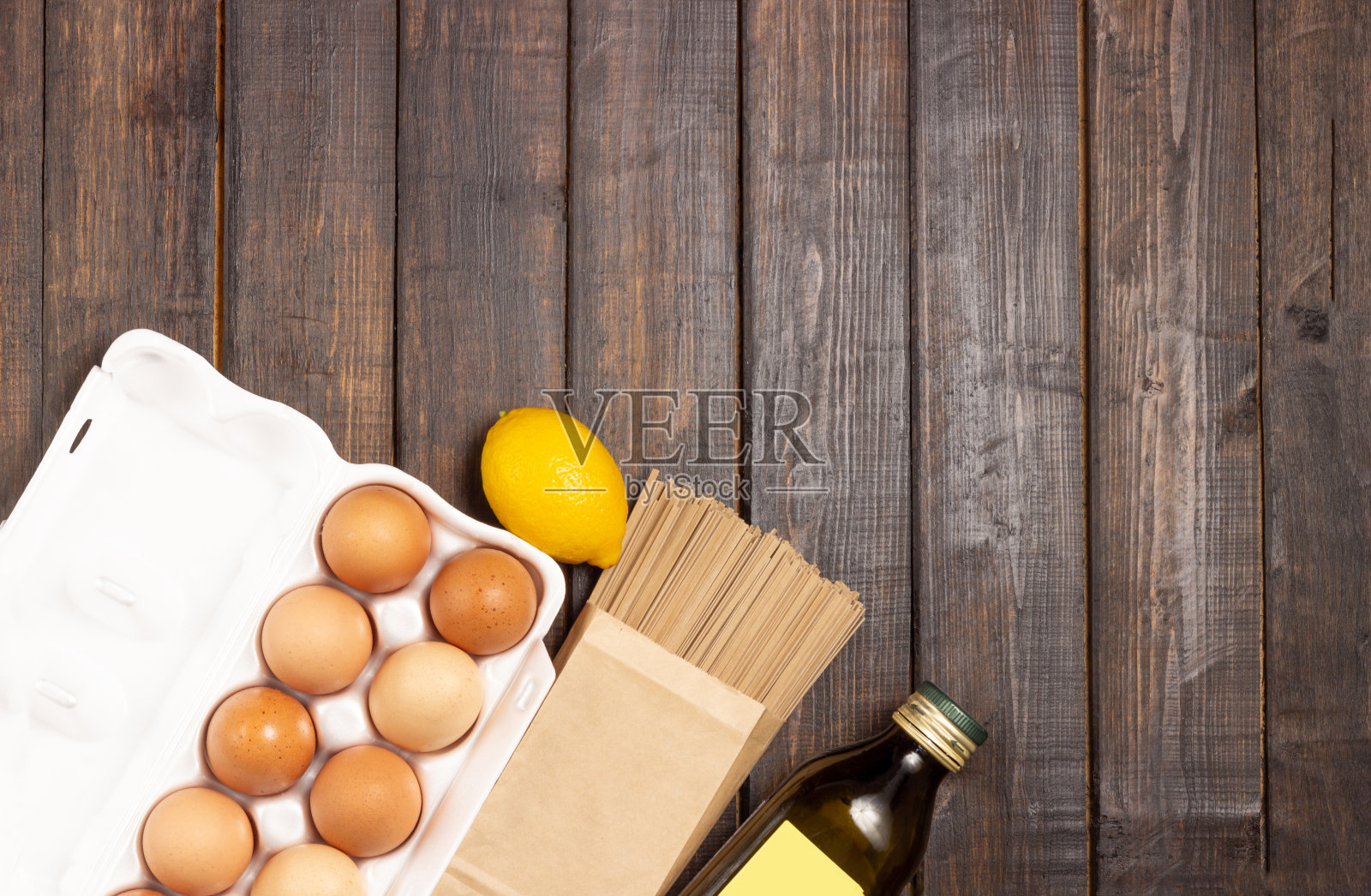 烹饪。木桌上放着鸡蛋、意大利面和橄榄油。照片摄影图片