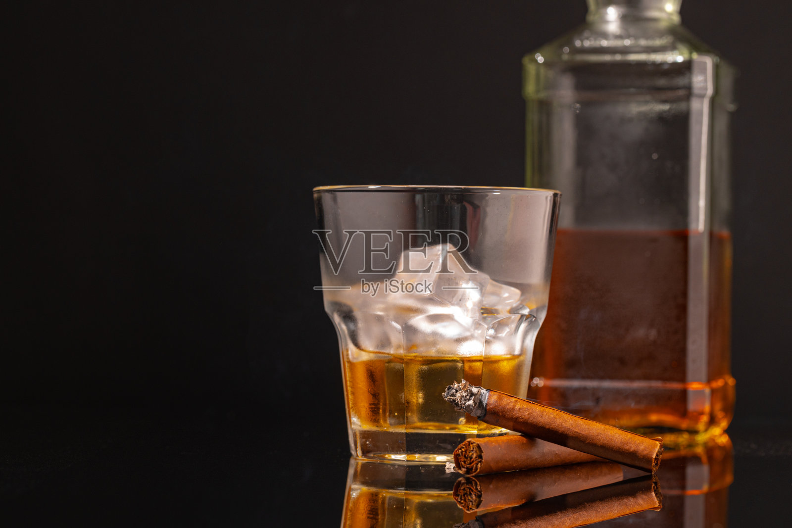 一杯威士忌和点燃的雪茄在黑色的背景照片摄影图片