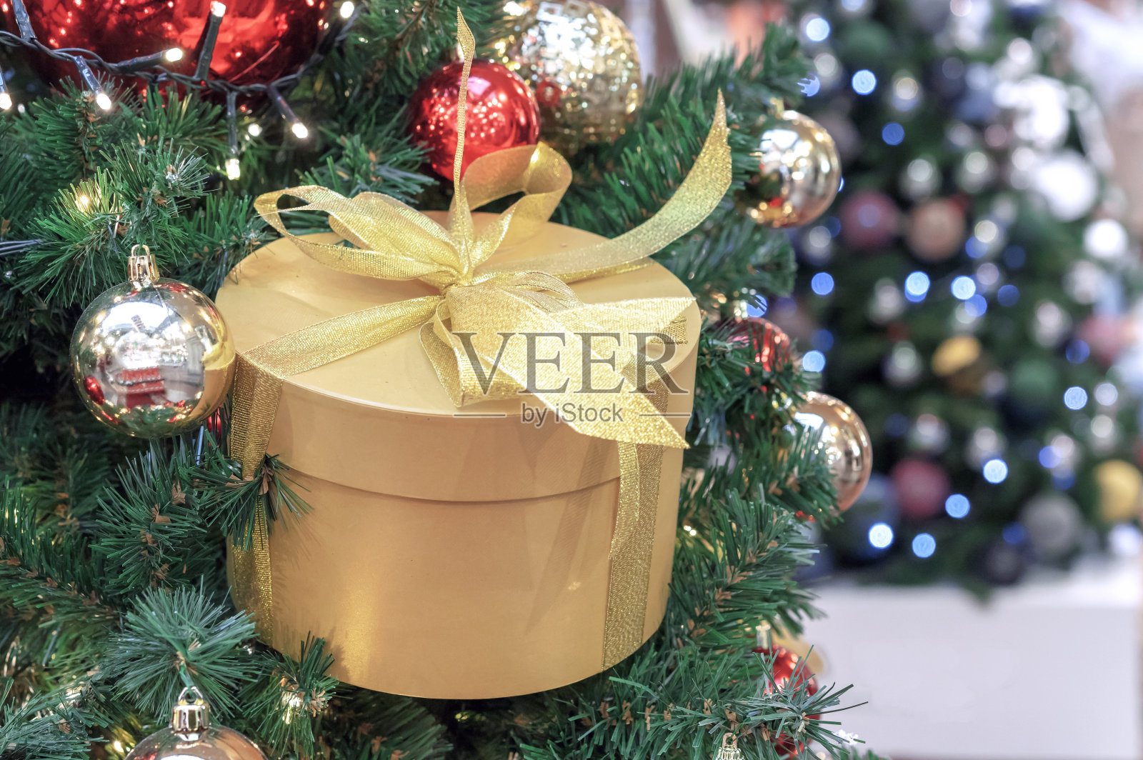 金色的圆形礼盒与蝴蝶结在圣诞树上。圣诞礼物。照片摄影图片
