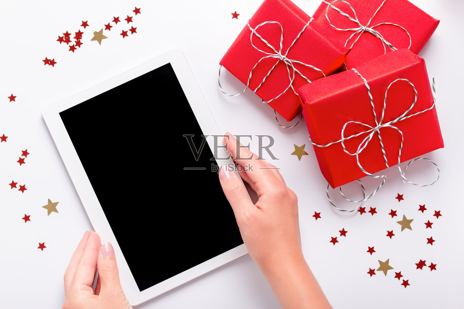 女人拿着平板与空白屏幕红色礼盒和闪闪发光的五彩纸屑在白色，俯视图，平躺照片摄影图片