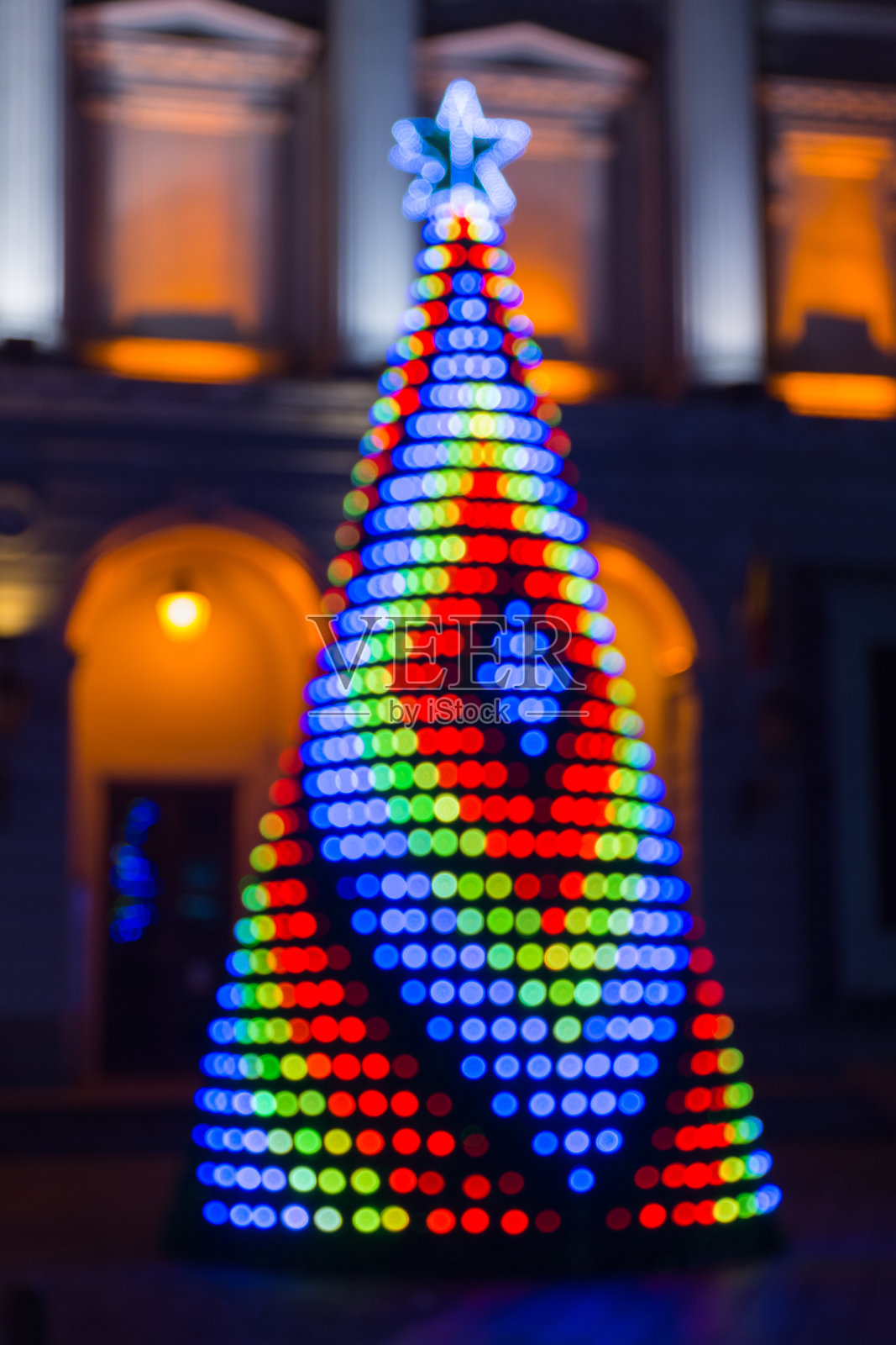 模糊的背景与彩色的圣诞树照亮了夜晚。照片摄影图片