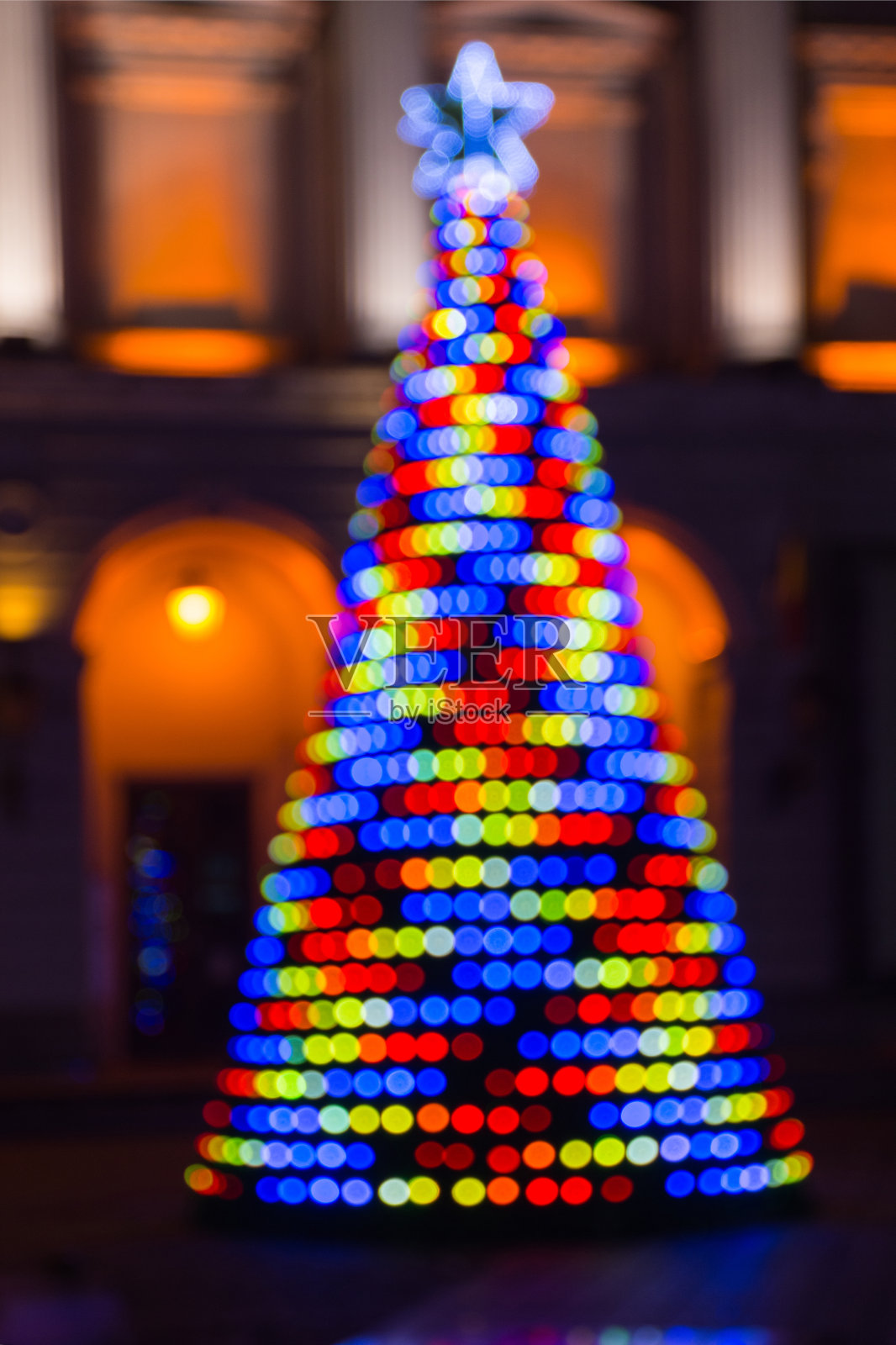 模糊的背景与彩色的圣诞树照亮了夜晚。照片摄影图片
