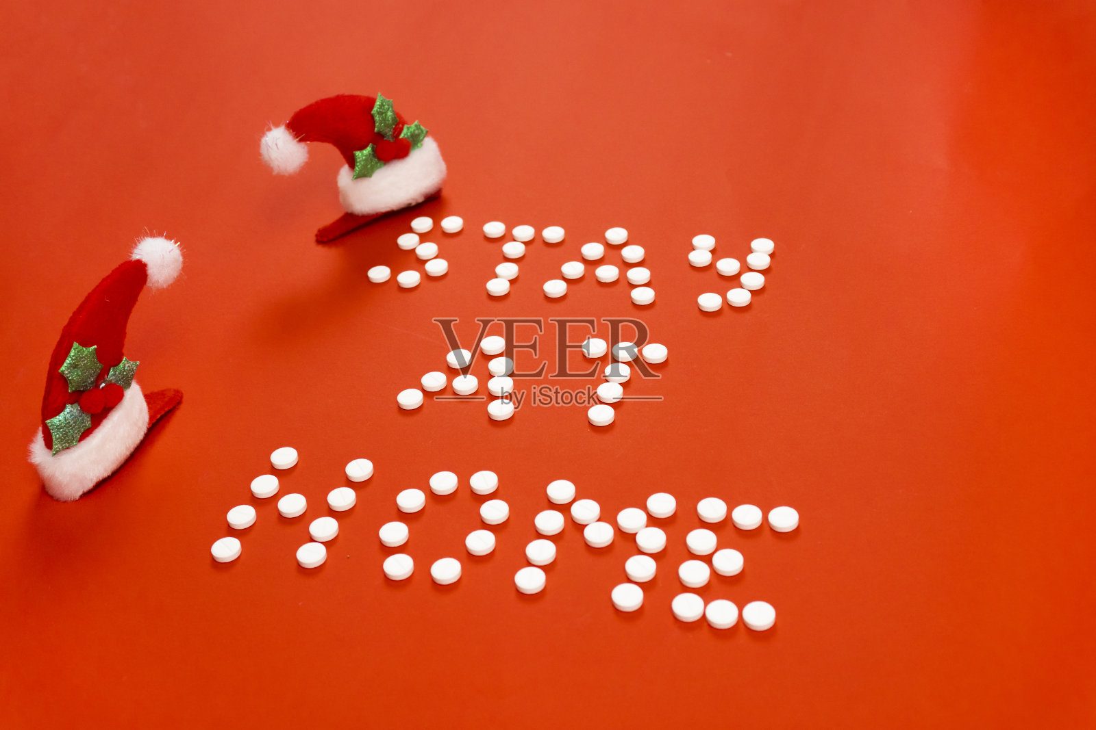呆在家里，红色背景上的圆形白色药丸。圣诞装饰品。照片摄影图片