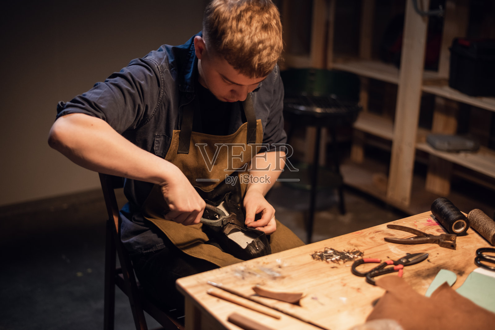 一位年轻的手工制鞋大师正在他的作坊里制作鞋子照片摄影图片
