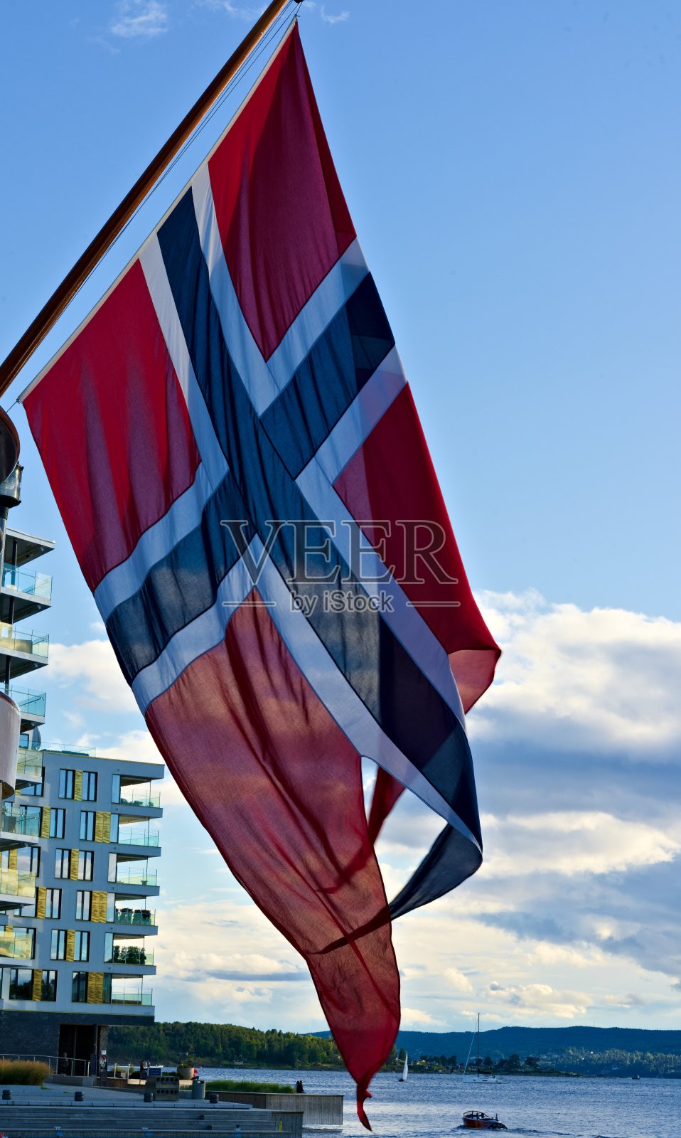 挪威官方国旗在风中飘扬，背景是蓝天。照片摄影图片
