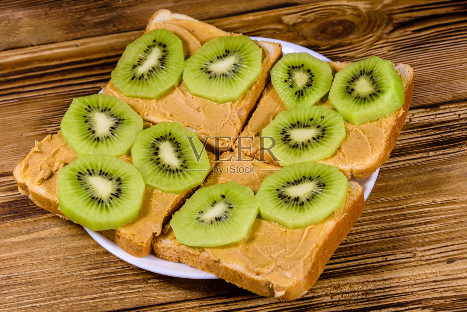 夹着花生酱和切片猕猴桃的三明治放在木桌上照片摄影图片