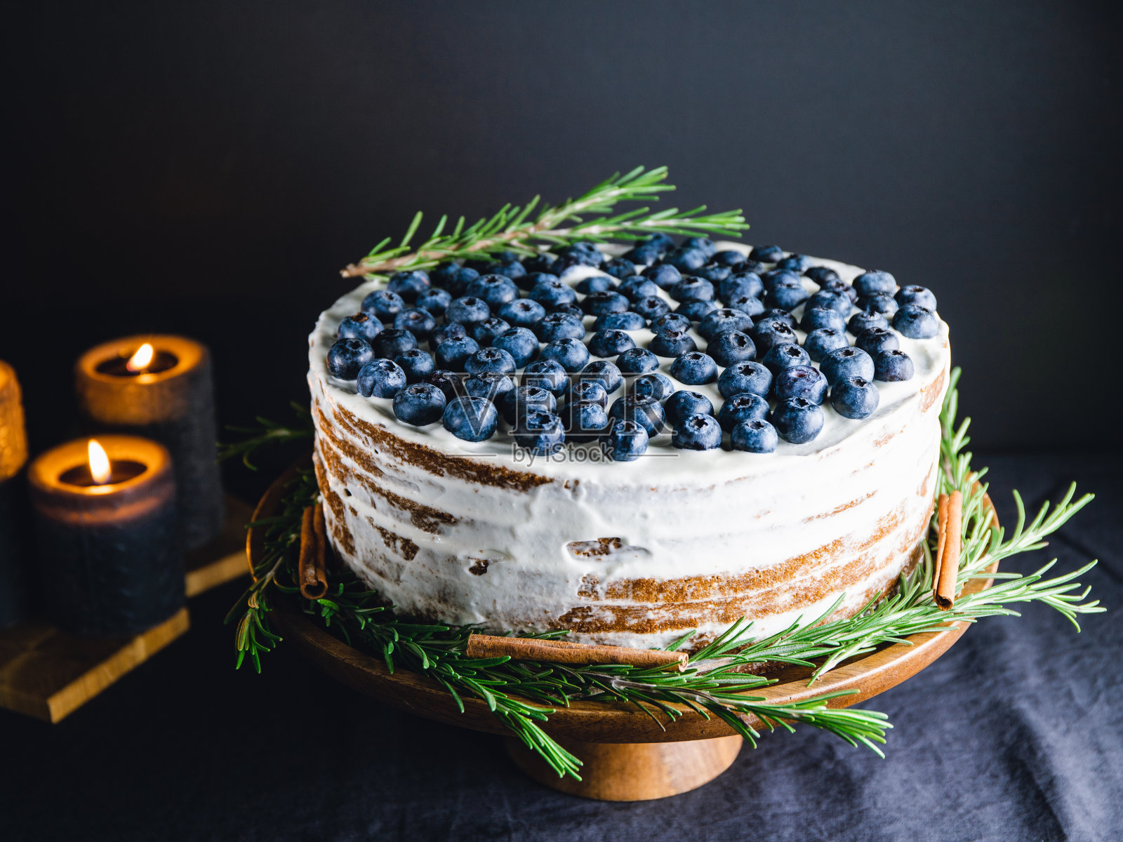 巧克力层蛋糕与新鲜蓝莓装饰迷迭香枝在木托盘在黑暗的内部。照片摄影图片