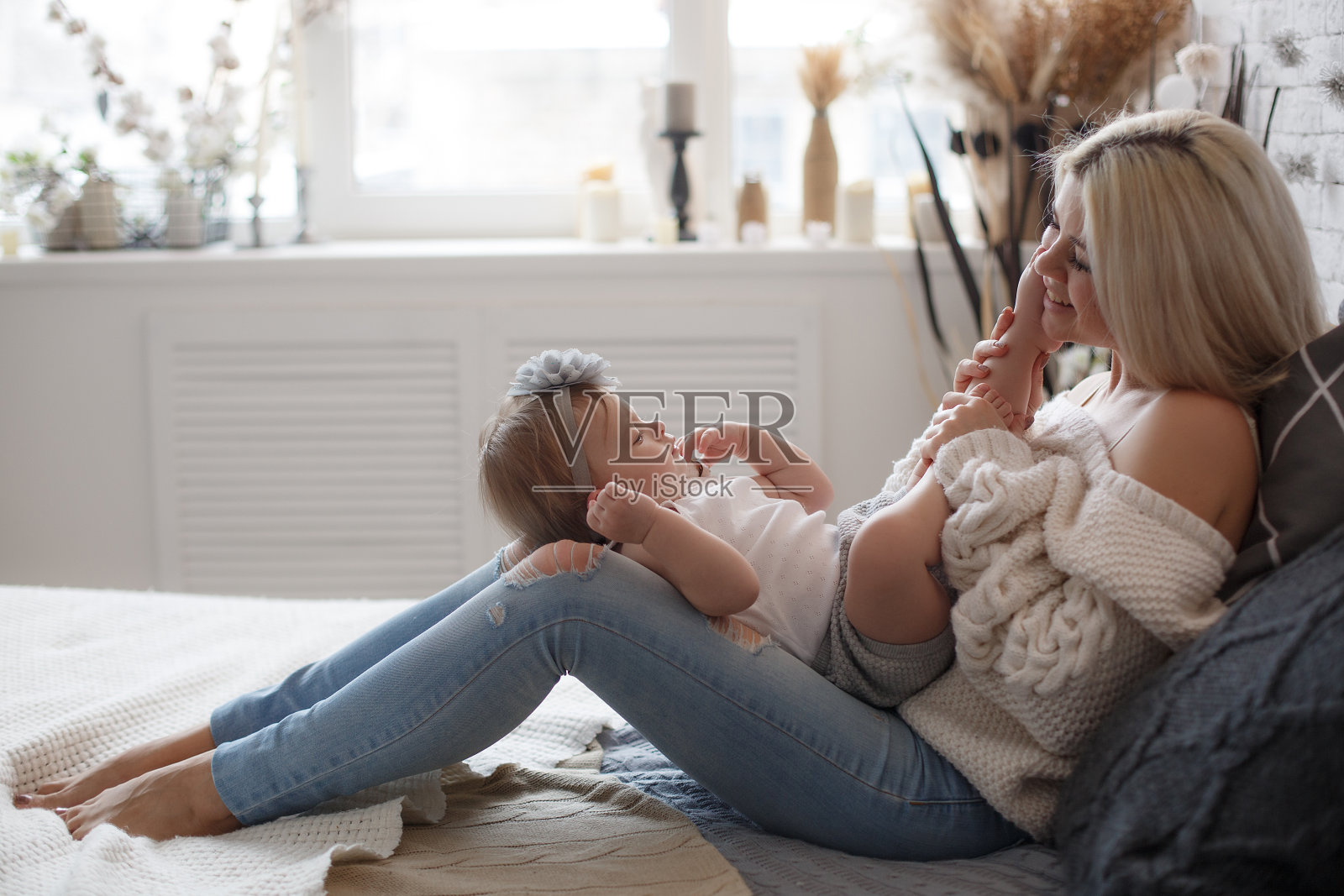 妈妈和小女儿在明亮的卧室里白色的床上玩得很开心照片摄影图片