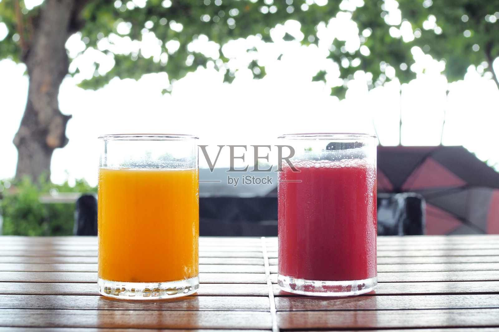 桌上放着几杯夏季冷饮、西瓜和橙汁。照片摄影图片