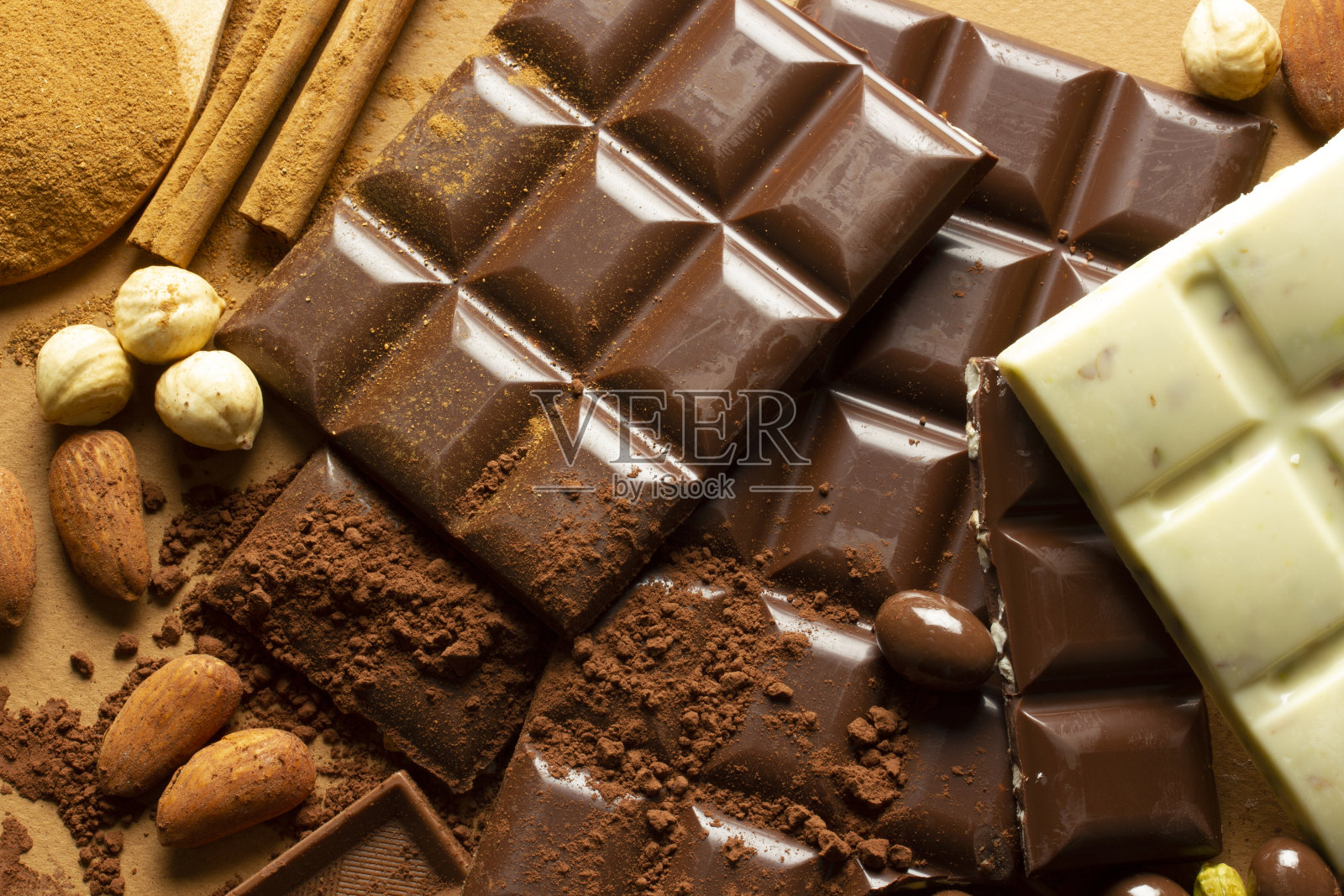 白巧克力和牛奶巧克力。杏仁、开心果、榛子。背景,纹理。照片摄影图片