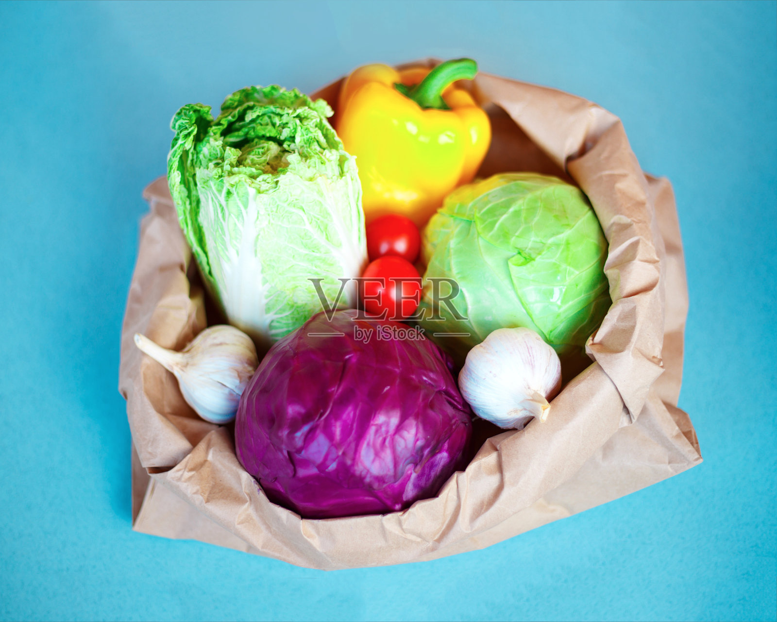 蓝色背景的纸袋上有新鲜的当地蔬菜照片摄影图片