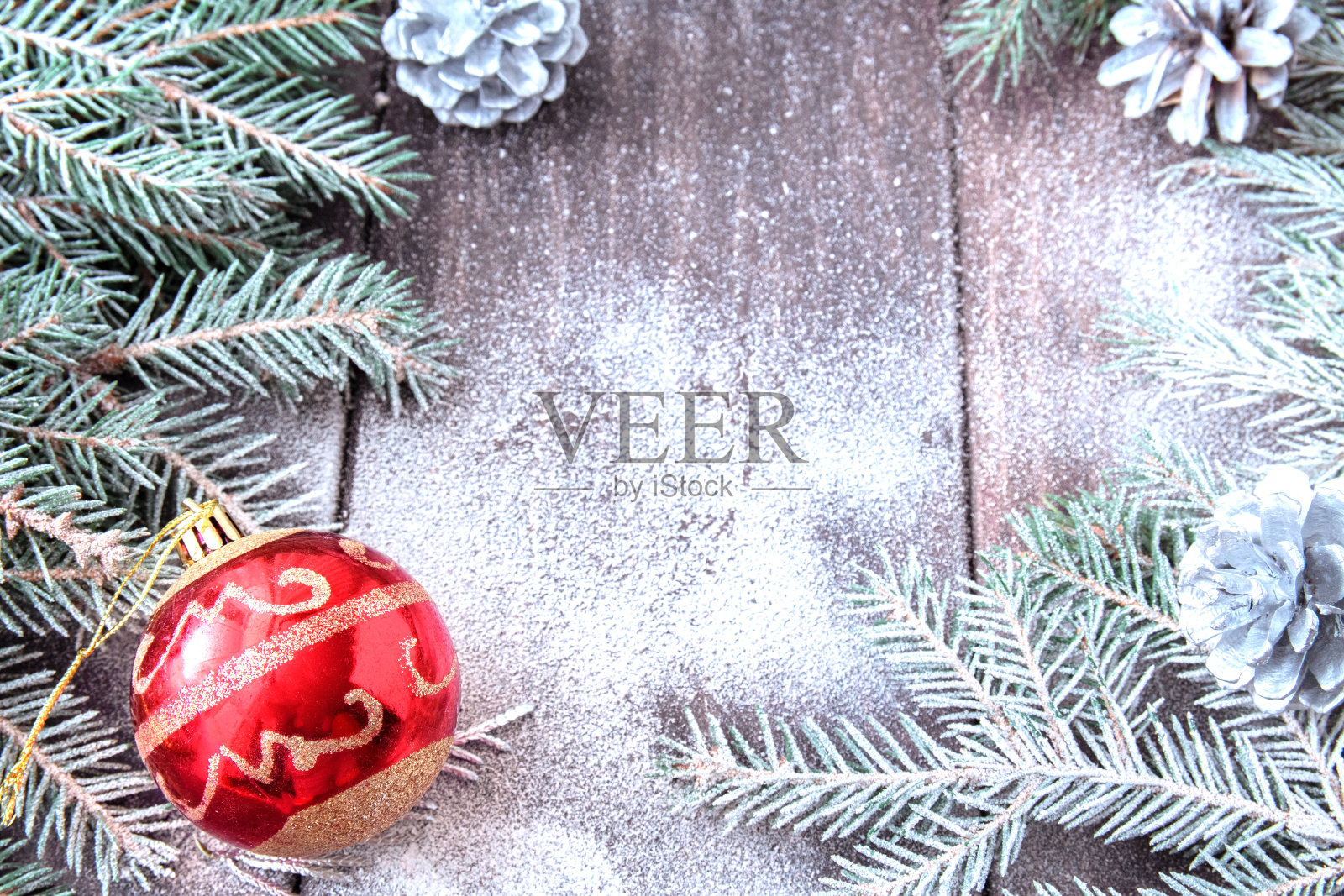 圣诞节的背景。白雪覆盖的冷杉树枝、松果和白雪覆盖的木板上的红色圣诞球。本空间照片摄影图片