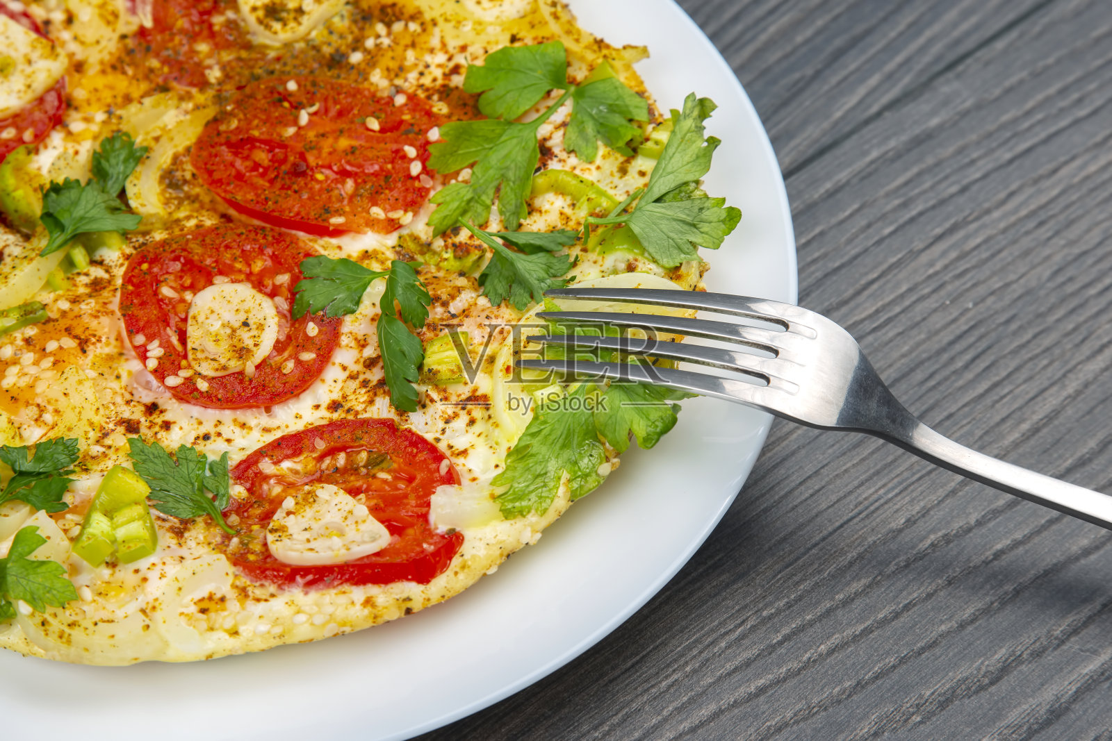 木桌上的白盘子里放着香草和蔬菜，煎熟的煎蛋卷照片摄影图片