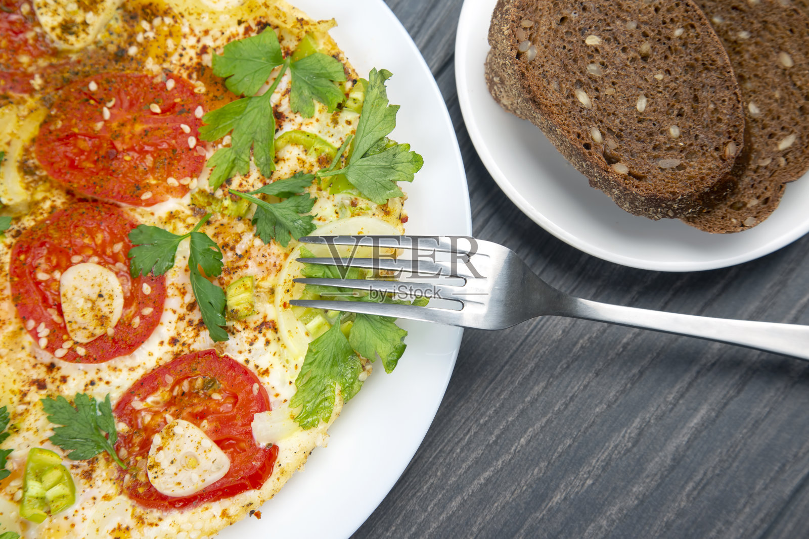 木桌上的白盘子里放着香草和蔬菜，煎熟的煎蛋卷照片摄影图片