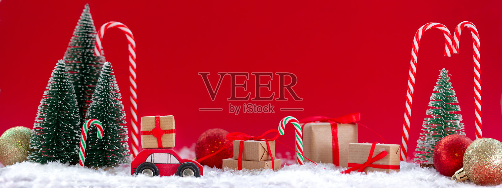 节日构图圣诞红车与礼盒在松林里许多不同的礼物在红色的背景。新年贺卡的概念照片摄影图片