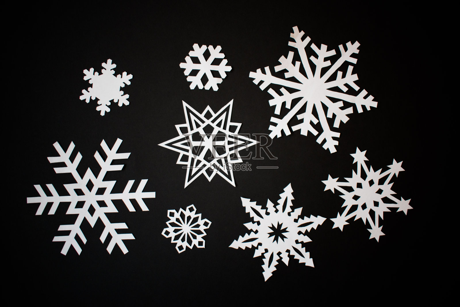白纸在黑色的背景上剪下雪花照片摄影图片