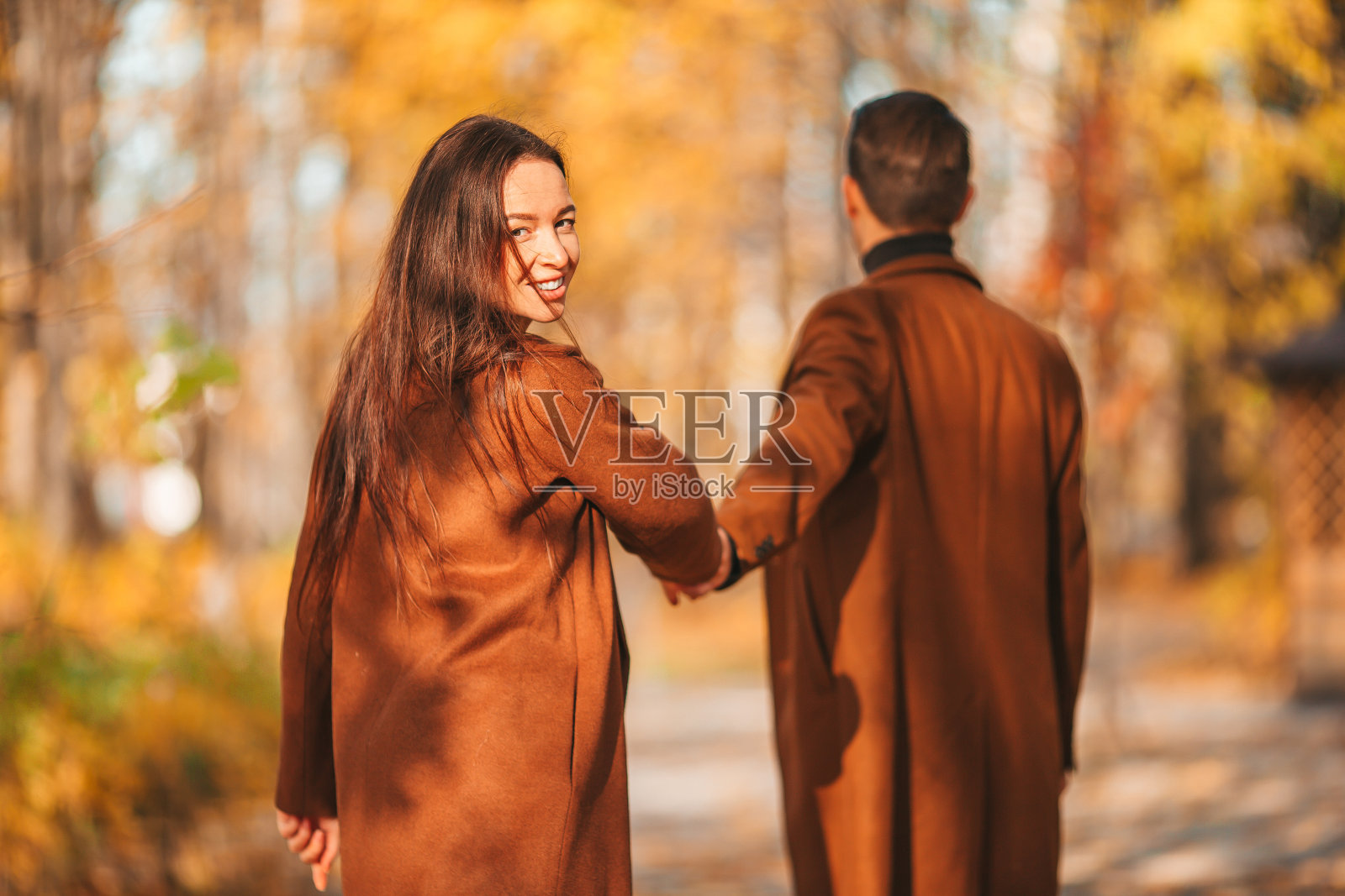 快乐的一家人在阳光明媚的秋天公园散步照片摄影图片