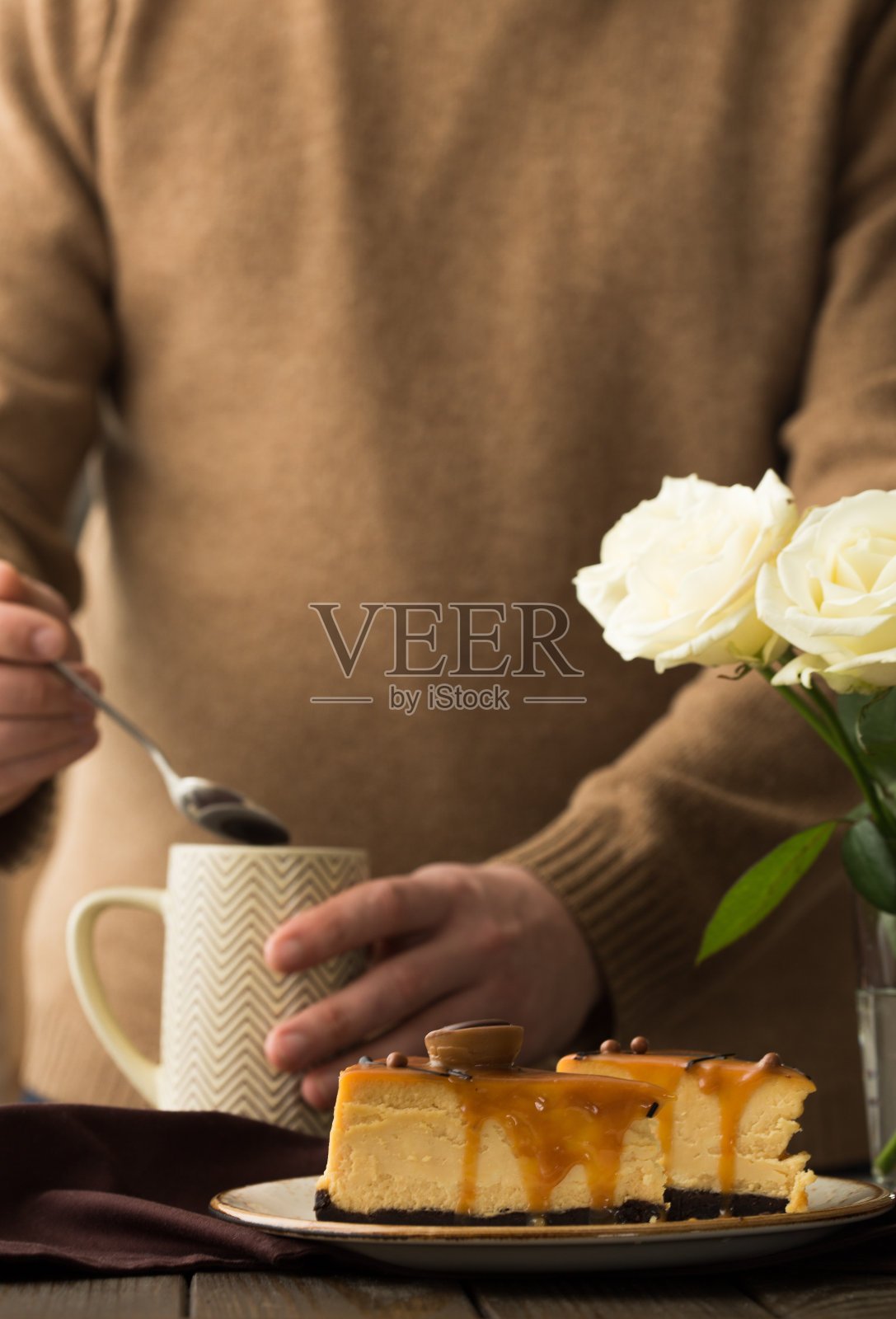 男人喝起司蛋糕与咸焦糖在棕色背景。为文本复制空间。照片摄影图片