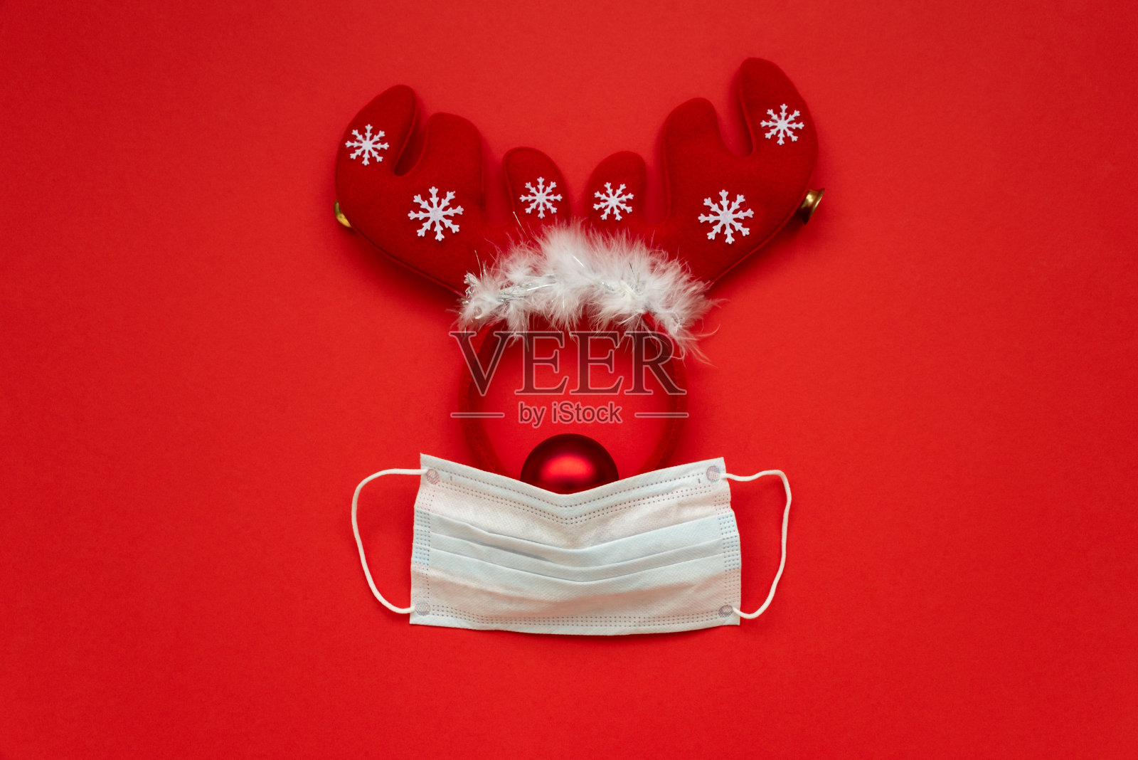 圣诞驯鹿制成的面具和装饰在红色的背景。平的。圣诞节或新年庆祝概念照片摄影图片