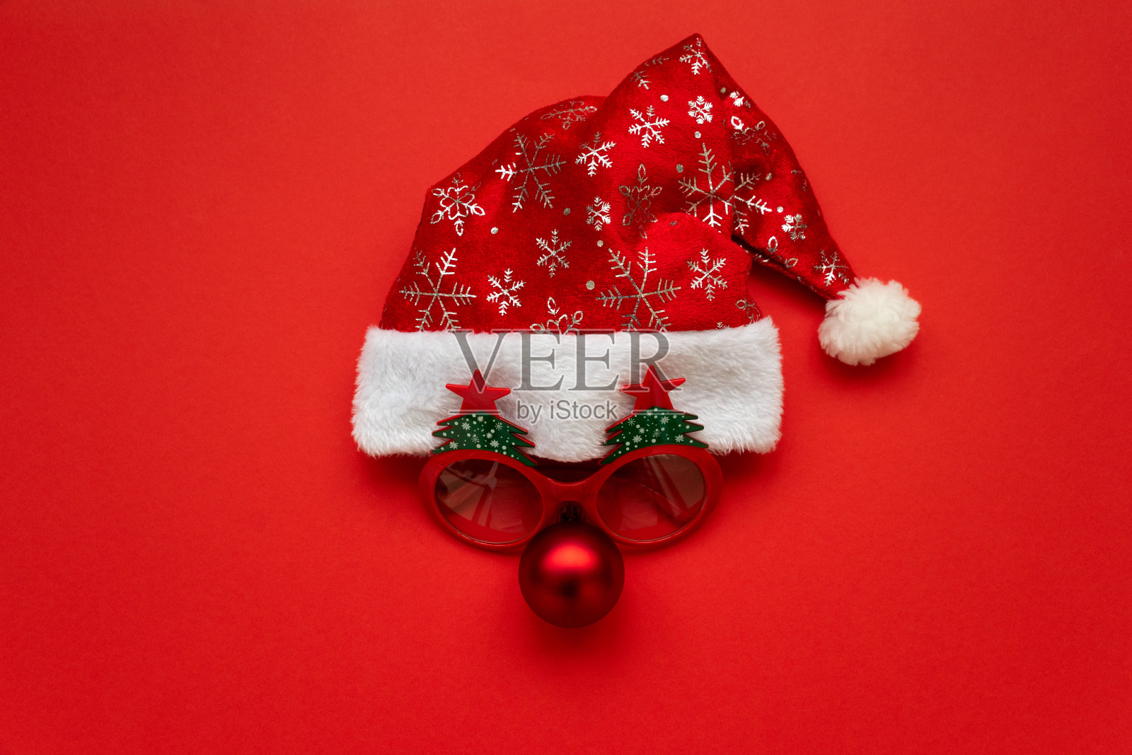 圣诞老人的帽子，眼镜和鼻子在红色的背景。平的。圣诞节或新年庆祝概念照片摄影图片