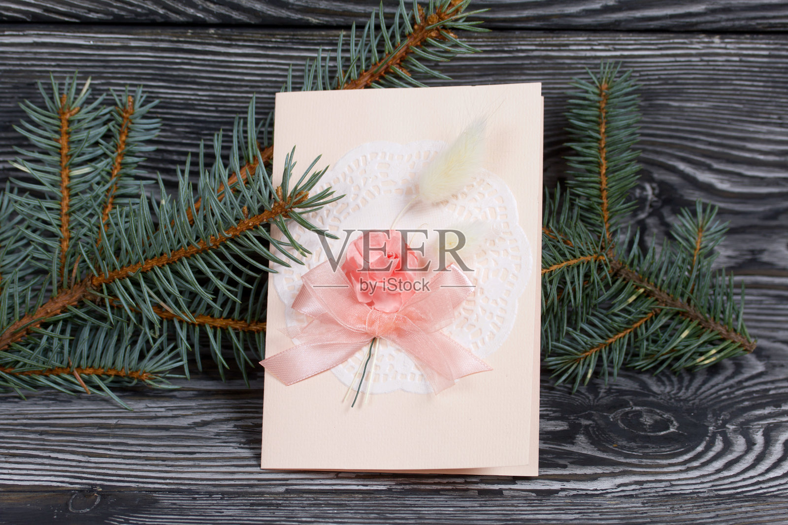 带有粉色阴影元素的贺卡。云杉分支。在黑色的松木板上。照片摄影图片