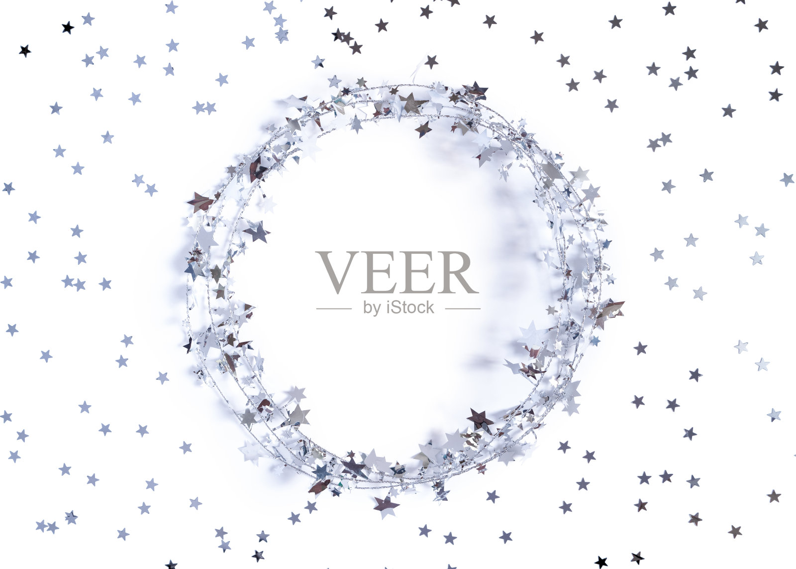 圣诞节的布局。一个由闪闪发光的花环制成的圆形框架上装饰着星星形状的五彩纸屑。白色背景。新年，冬天的概念。贺卡。平铺，拷贝空间。照片摄影图片