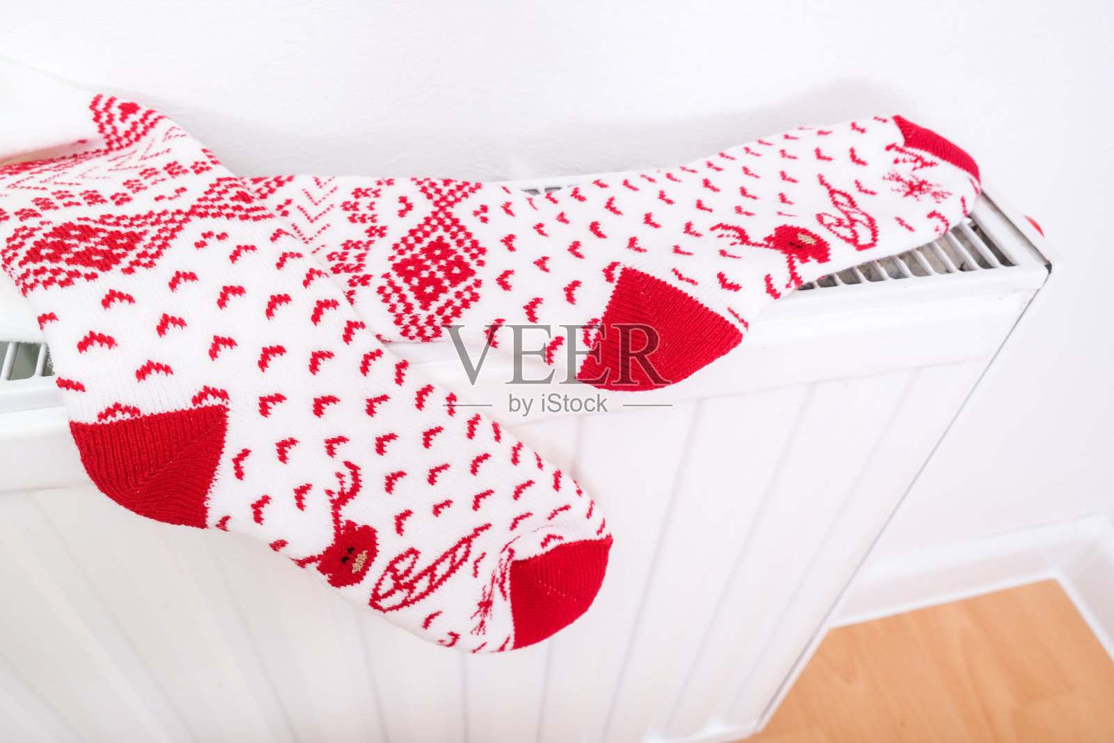 白色和红色的圣诞袜子挂在暖暖的中央暖气片上，寒假回家心情好照片摄影图片