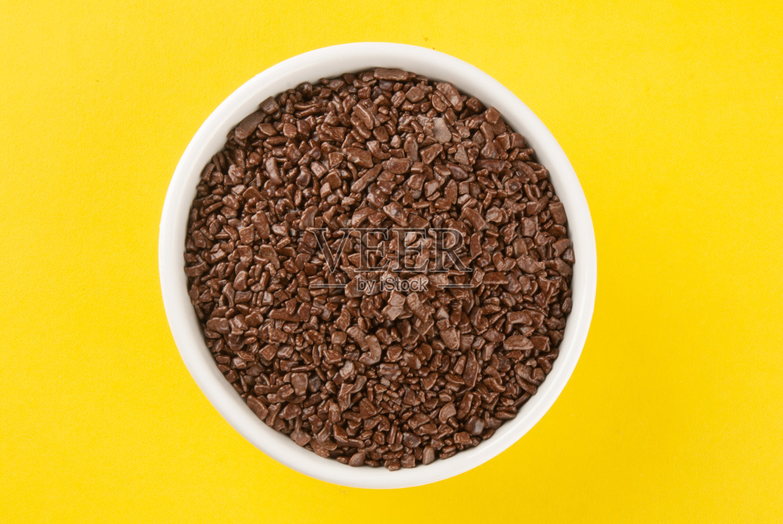 粉状巧克力，白色碗底，黄色背景。照片摄影图片