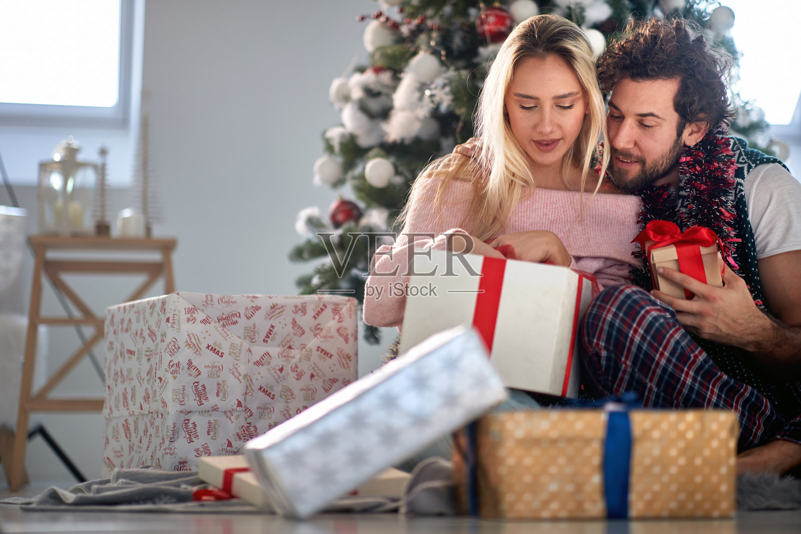 一对相爱的年轻夫妇坐在家里期待着圣诞礼物。圣诞节，关系，爱，相聚照片摄影图片