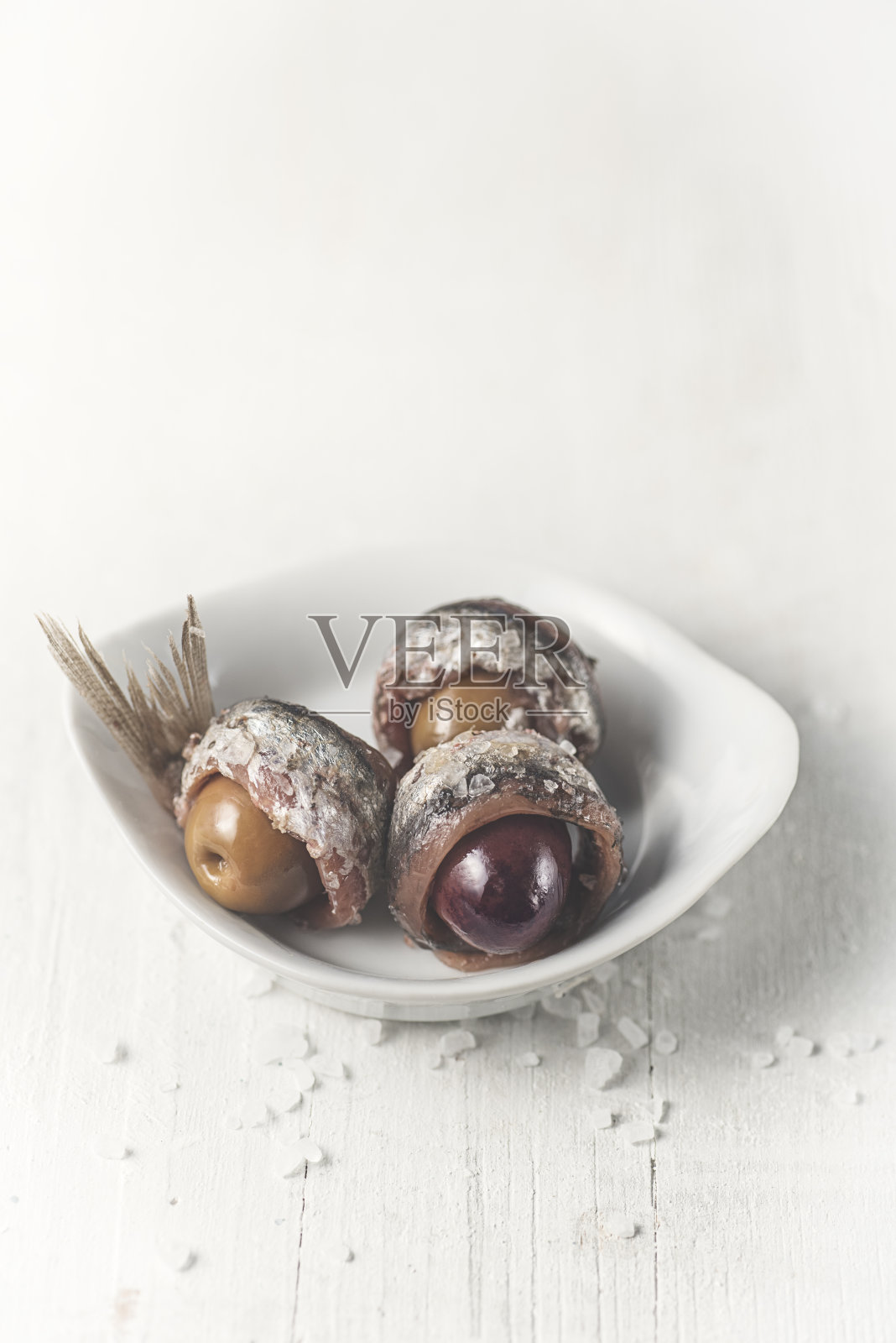 盐腌凤尾鱼地中海菜肴食谱在白色盘子与橄榄在白色的背景照片摄影图片