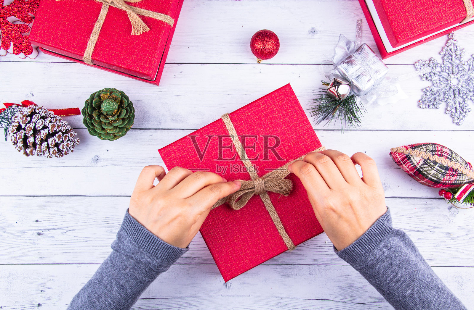 圣诞节的背景。在白板上有彩色闪亮的圣诞装饰的礼盒，女孩拿着新年礼盒。照片摄影图片