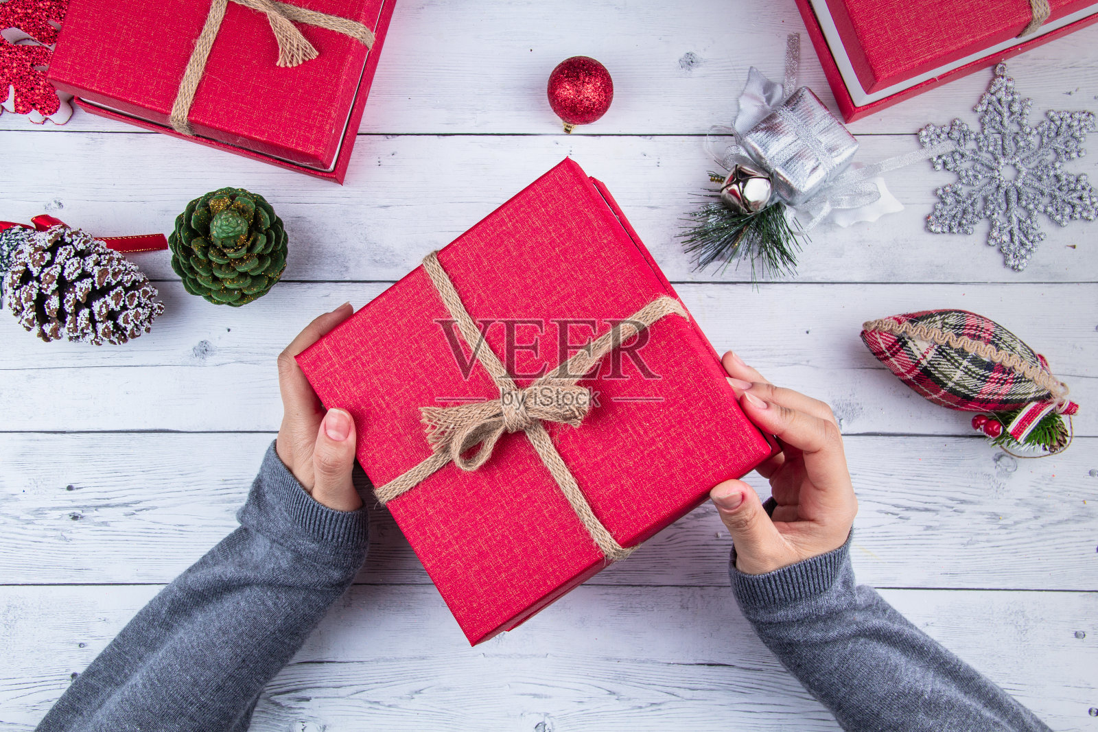 圣诞节的背景。在白板上有彩色闪亮的圣诞装饰的礼盒，女孩拿着新年礼盒。照片摄影图片