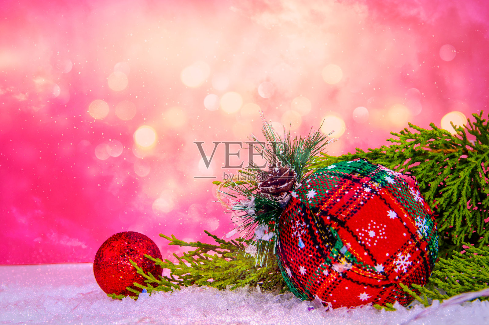 特写红色的圣诞装饰品，雪地上的雪和松树，红色的墙照片摄影图片