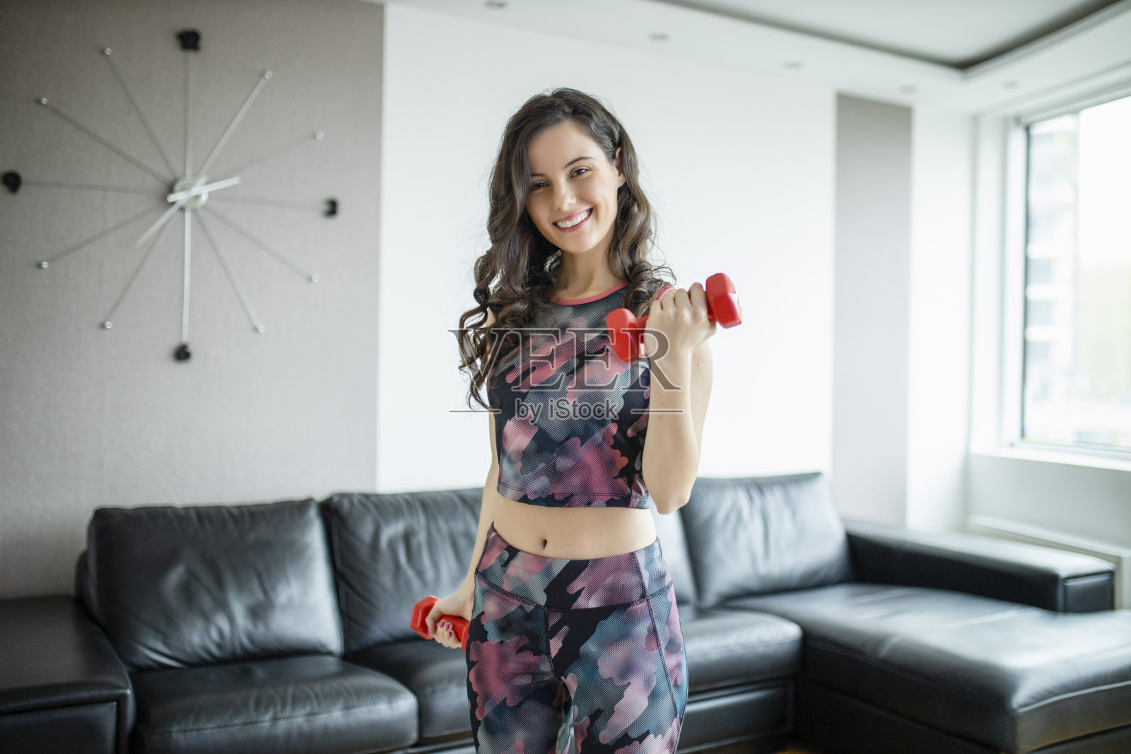 年轻的女运动员在她的家里举重和锻炼照片摄影图片