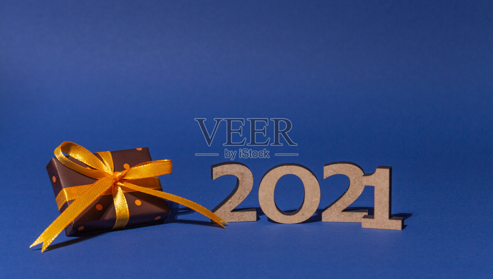 题词2021和礼盒与彩色纸与圆点系黄色丝带在蓝色背景。圣诞和新年贺卡，横幅，广告概念。照片摄影图片