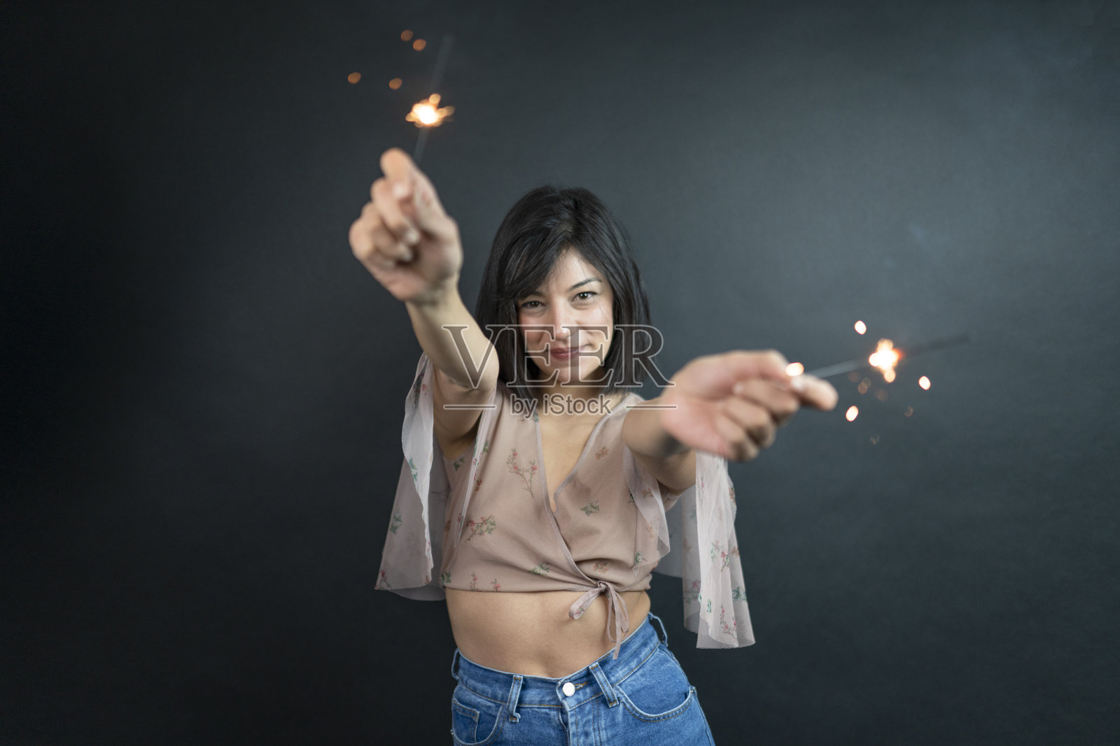 特写照片的愉快的白人女孩拿着孟加拉灯。快乐的年轻女子的肖像在红色睡衣孤立的黑色背景与火花照片摄影图片