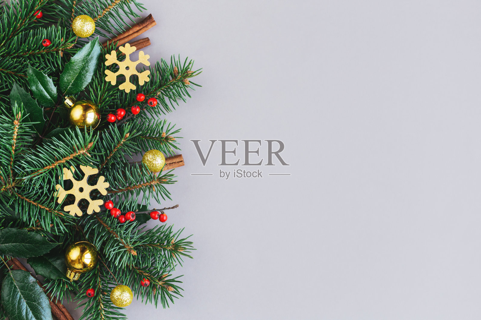 圣诞背景有云杉树枝，红色浆果，松果，肉桂棒和金色的雪湖。假日环保概念。灰色背景。照片摄影图片