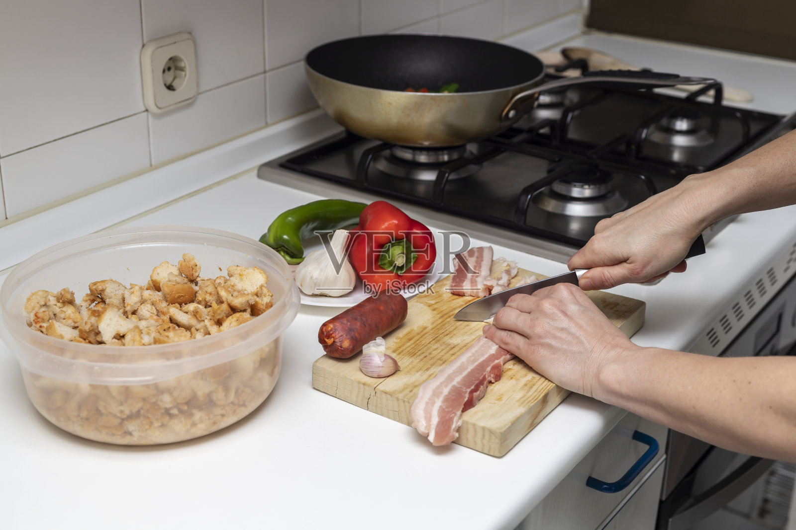 手切熏肉。Migas de Extremadura，传统的西班牙家常菜，用培根，西班牙香肠，大蒜，面包屑，红绿辣椒和辣椒粉，放在厨房的柜台上照片摄影图片