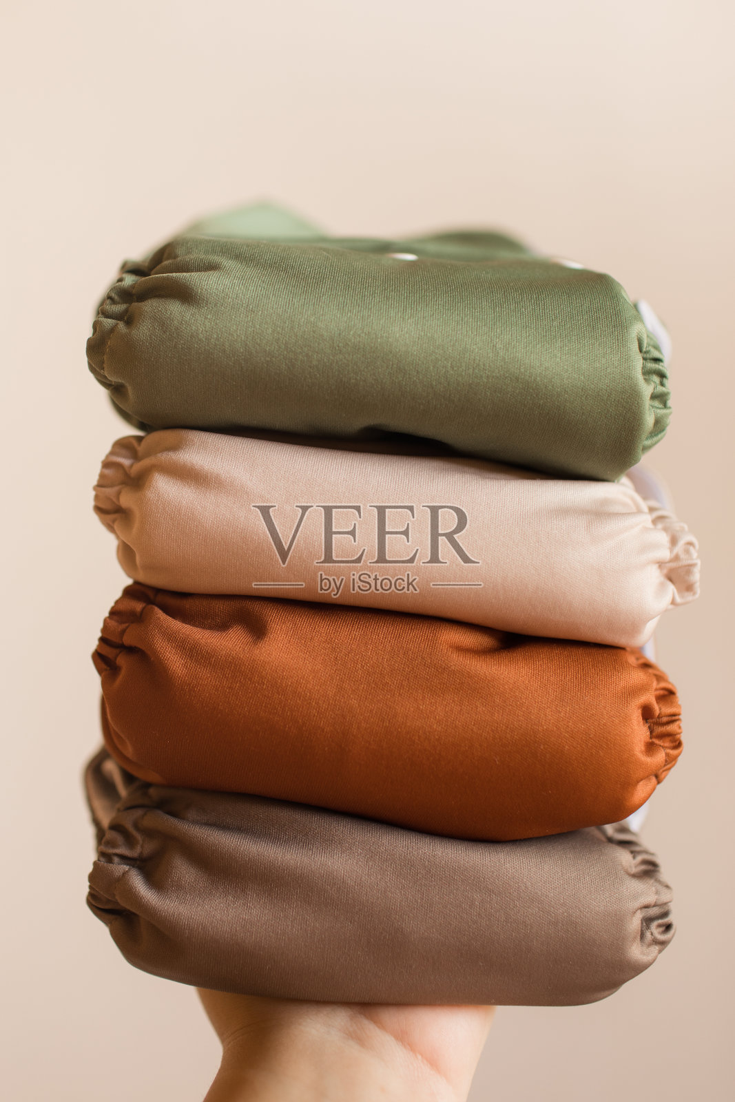 在明亮的自然光下，一个女人拿着一堆现代中性单色可重复使用的布尿布照片摄影图片