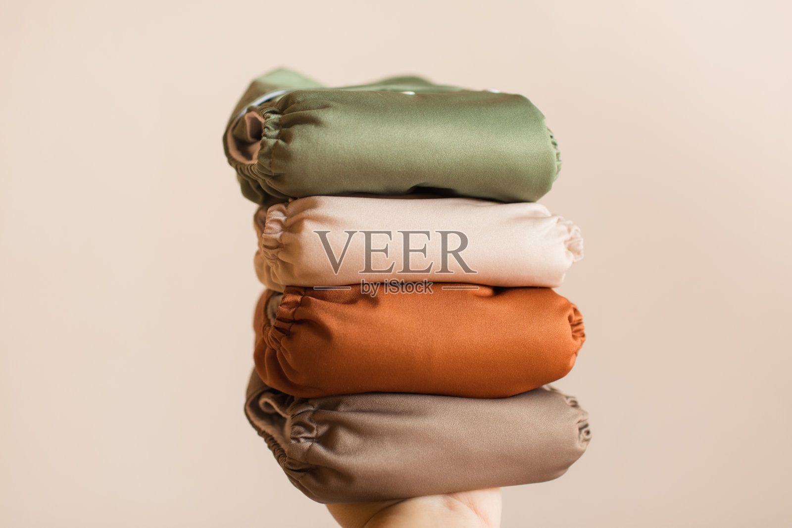 在明亮的自然光下，一个女人拿着一堆现代中性单色可重复使用的布尿布照片摄影图片