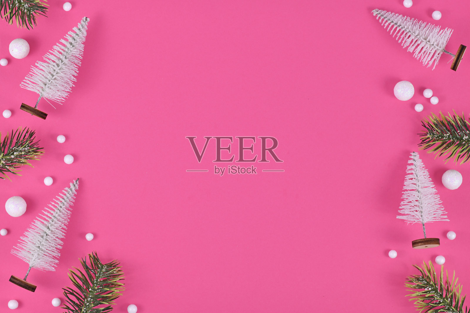 白色微型圣诞树，冷杉树枝和雪球装饰侧面的粉红色背景照片摄影图片