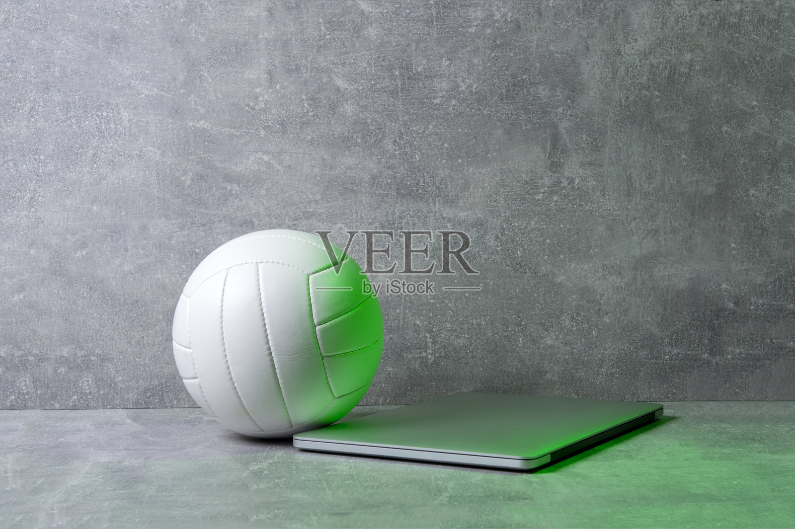 灰色背景上的白色排球和灰色笔记本电脑。在线运动的概念照片摄影图片