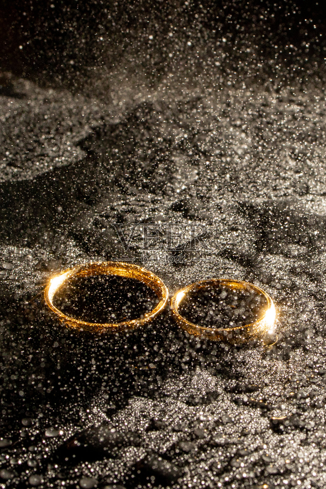 黑色背景上的两个金婚戒。照片摄影图片