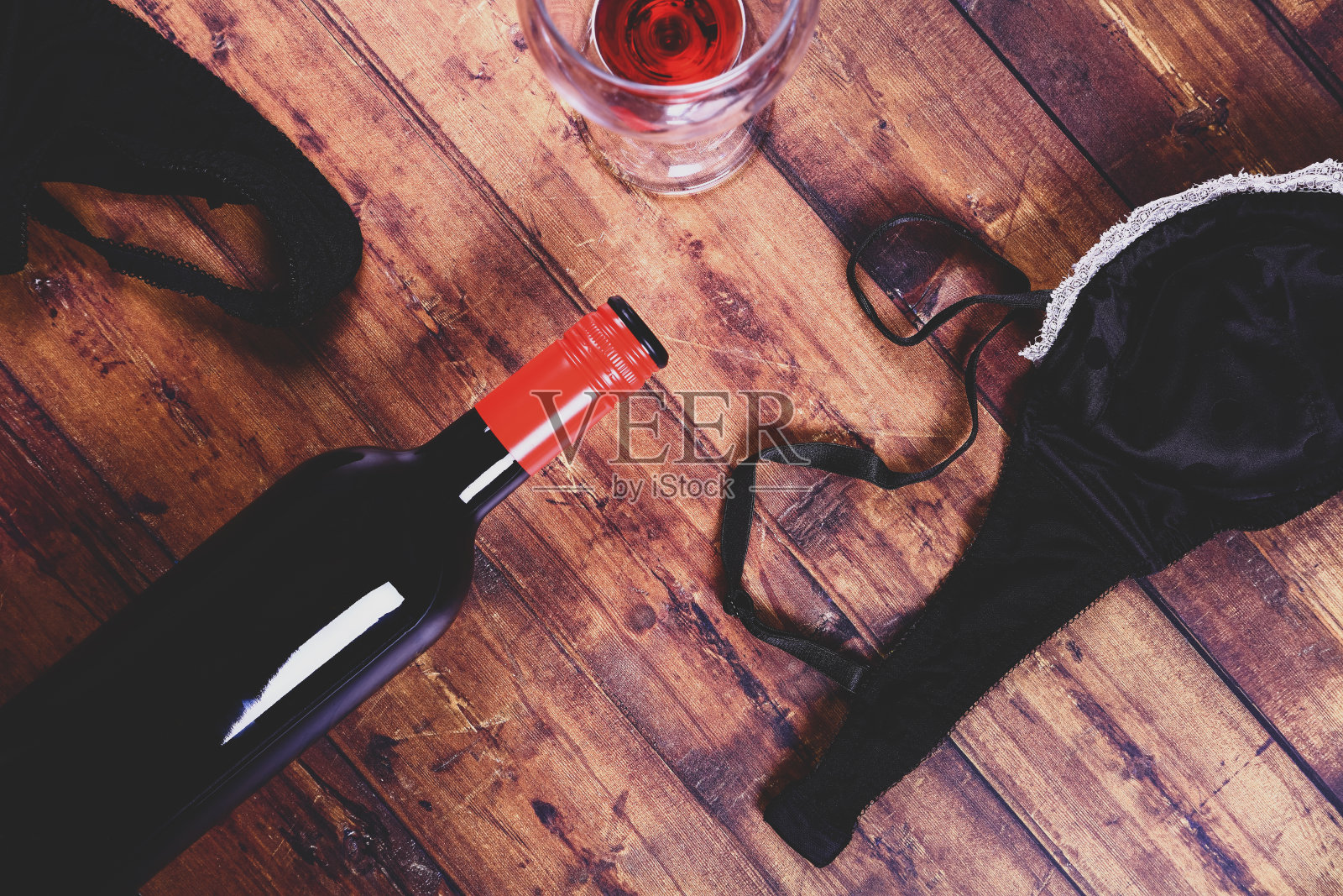 女士的黑色胸罩和短裤配一瓶红酒和酒杯照片摄影图片