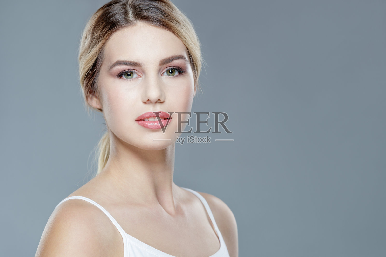 漂亮的金发年轻女人穿着背心，头发向后看着镜头照片摄影图片